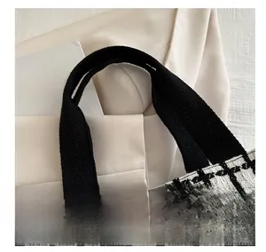 Close-up of black and white checkered tweed fabric and canvas handle on a tote bag