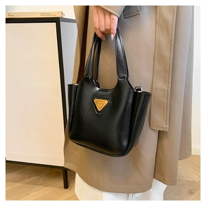 Close-up of black textured leather tote bag featuring a golden triangle logo and dual handles