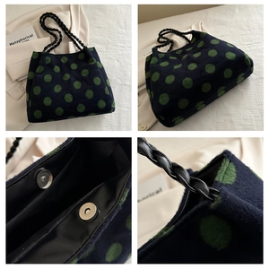 Detail of navy knit tote bag with green dots featuring woven leather handles and magnetic snap