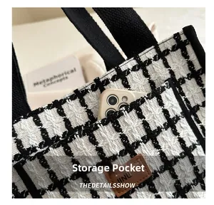 Detail view of the black and white plaid tote bag featuring a functional side pocket for a phone
