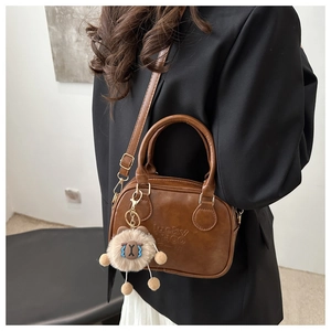 Detail view of brown vintage handbag with lucky embossing and cute plush charm