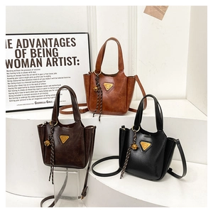 Detailed shot of retro faux leather tote bags in black and brown with tassel charms