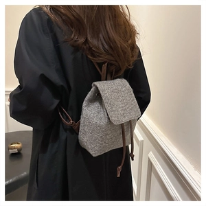 Detail view of grey wool tweed backpack featuring brown leather straps and drawstring closure