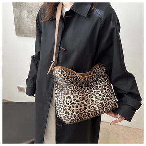 Detail of leopard print tote bag featuring brown leather straps and textured fabric surface