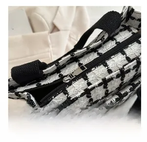 Detail view of the smooth silver metal zipper on the black and white checkered tote bag