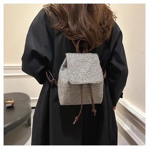 Detail of grey woolen backpack with tweed texture and brown leather drawstring closure