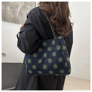 Detail view of winter plush tote bag with green polka dots and chunky black chain strap