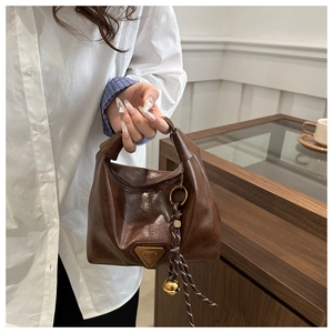 Detail of vintage brown oil wax leather hobo bag with metal logo and knotted handle strap