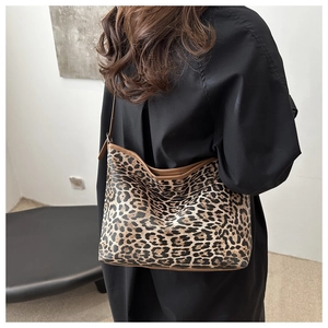 Fashionable leopard print tote bag with brown leather trim shown on a model's shoulder