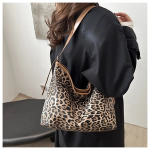 Detail of leopard print tote bag with brown leather shoulder strap shown on model