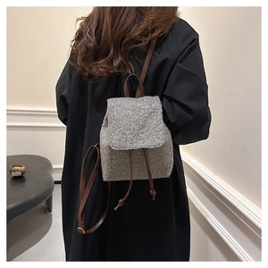 Close-up of grey tweed texture and leather strap on a minimalist women's backpack