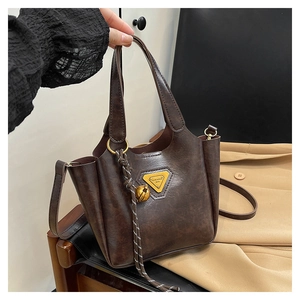 Detail of dark brown lychee texture tote with triangle metal logo and detachable strap