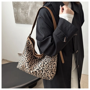 Detailed close-up of leopard print canvas tote bag with brown leather strap detail