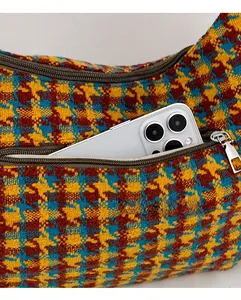 Close-up of smooth metal zipper and houndstooth tweed fabric texture on the dumpling bag