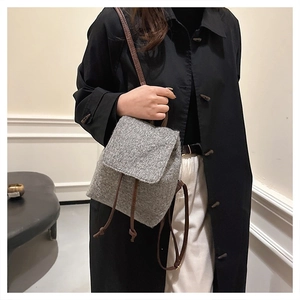 Gray wool backpack with brown leather drawstrings worn over a black trench coat