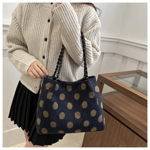 Detail showing plush navy tote bag with large brown polka dots held by a model