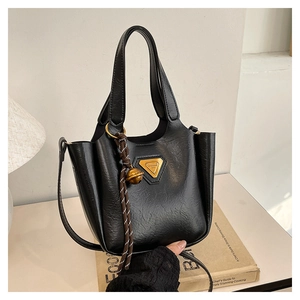 Detail of black wrinkled leather tote with gold triangle logo and woven handle decor