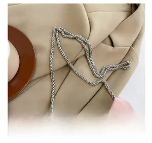 Détail du sac plissé rose avec bandoulière en chaîne argentée et bijou papillon