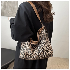 Detail view of large leopard print hobo bag with brown leather strap on a model shoulder
