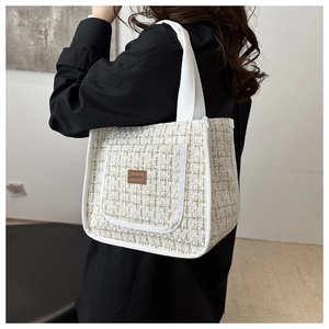 Close-up of white tweed tote bag with Jingpin leather patch worn by model in black outfit
