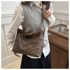 Detail of leopard print tote bag with brown leather straps and spacious interior design