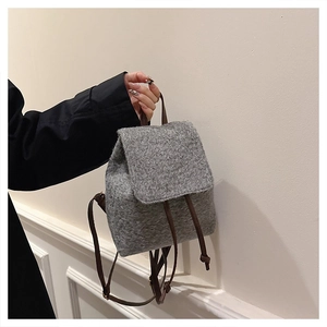 Detailed close-up of grey wool-textured backpack with soft plush fabric and brown straps