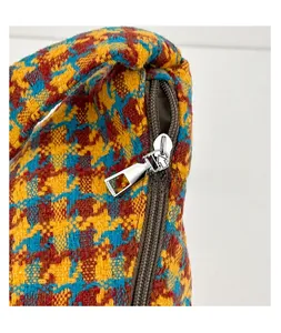 Detailed view of high-quality smooth metal zipper on vintage plaid fabric shoulder bag