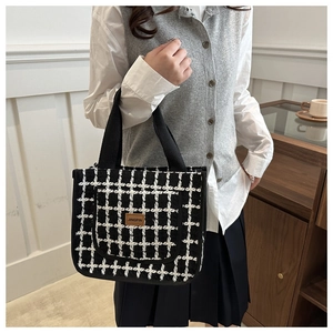 Close-up of black and white houndstooth tweed texture with brown leather logo patch
