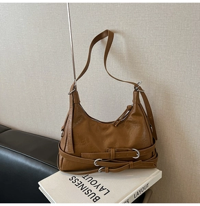 Détail d'un sac à main marron en cuir grainé avec boucles métalliques rétro et ceintures