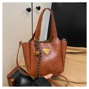 Detail of vintage brown leather tote bag with metallic logo and bell charm accessory