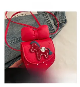 Detail of red girls crossbody bag featuring embroidered horse and bow decoration