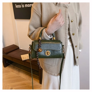 Detail of dark green leather handbag with metal ring lock and decorative knot tassel