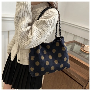 Detail of blue knit tote bag with gold polka dots and black woven texture handle