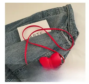 Close-up of red girl's mini crossbody bag with a large bow on a denim jacket background