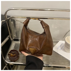 Detailed view of brown vintage leather bag featuring a gold triangle logo and strap