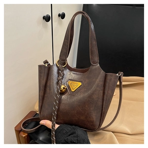Detail of vintage coffee brown faux leather tote bag with gold triangle plaque and woven tassel