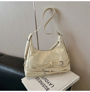 Détail du sac bandoulière en cuir crème avec boucles argentées et texture plissée