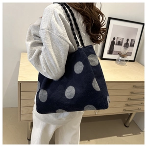 Detail of navy blue knitted tote bag with grey dots and thick black woven strap