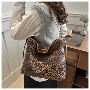 Detail of large leopard print tote bag with brown straps worn over the shoulder