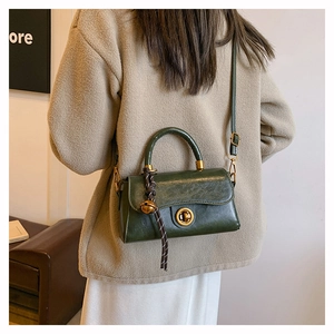 Detail view of dark green retro leather handbag with golden twist lock and charm