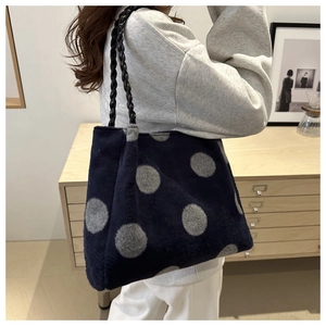 Detail of soft plush tote bag with grey polka dots and black woven handles