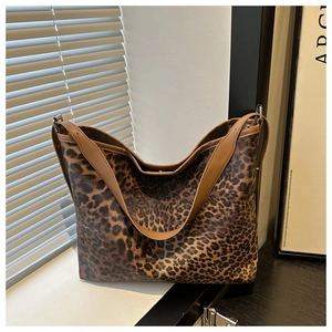 Close-up of leopard print tote bag texture and brown shoulder strap on window sill