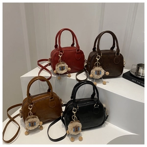 Mini Boston bags in four colors with plush charms and shoulder straps on white display
