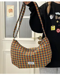 Close-up of vintage plaid dumpling bag featuring colorful woven texture and side fabric label