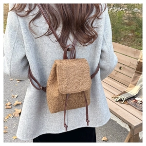 Close-up of brown wool mini backpack with leather straps on a park bench