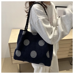 Detailed view of plush polka dot tote bag with black woven handles for winter fashion