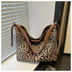 Detail of leopard print tote bag with brown leather straps and adjustable metal buckle
