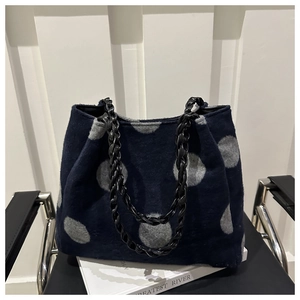 Detail of navy blue fuzzy tote bag with gray polka dots and black chain strap