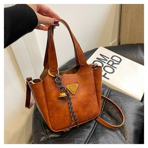 Detail of vintage brown leather tote bag featuring a triangle logo and bell charm