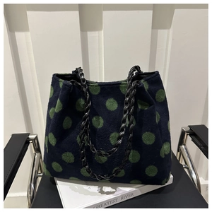 Close-up of wool tote bag with large green polka dots and leather woven chain strap